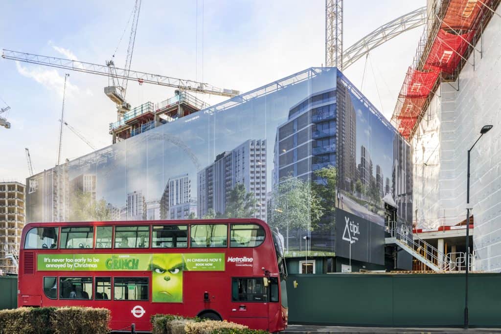 Image showing a printed building wrap hiding scaffolding with a red bus