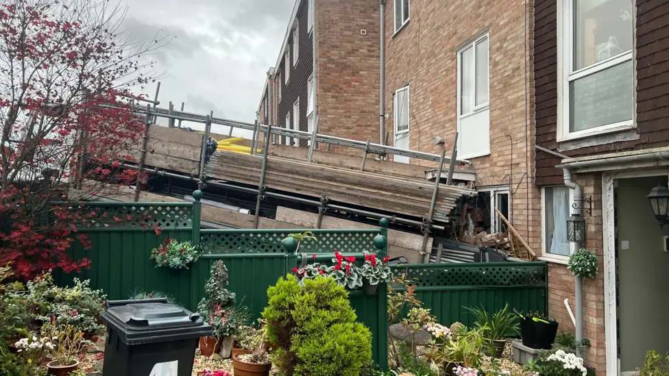 A scaffolding lorry has rolled into a house in Oldland Common near Bristol, damaging cars and a property. No one was injured, police said.